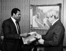 30 October 1985, United Nations Headquarters, New York: Mr. Serge Elie Charles (Haiti), Vice-Chairman of the Special Committee against Apartheid, presenting a check for Mrs. Winnie Mandela, whose house was set on fire and destroyed earlier on August, to Secretary-General Javier Perez de Cuellar (right). 