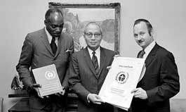 Mr. Maurice F. Strong, Secretary-General of the United Nations Conference on the Human Environment (right), shows United Nations Secretary-General U Thant a design for the official Conference poster. To the left is Mr. Keith Johnson (Jamaica), Chairman of the Preparatory Committee for the Conference.
